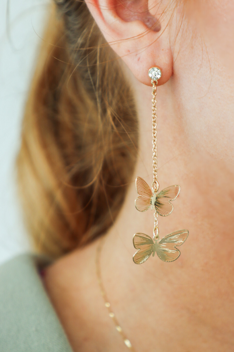 girl wearing gold butterfly earrings