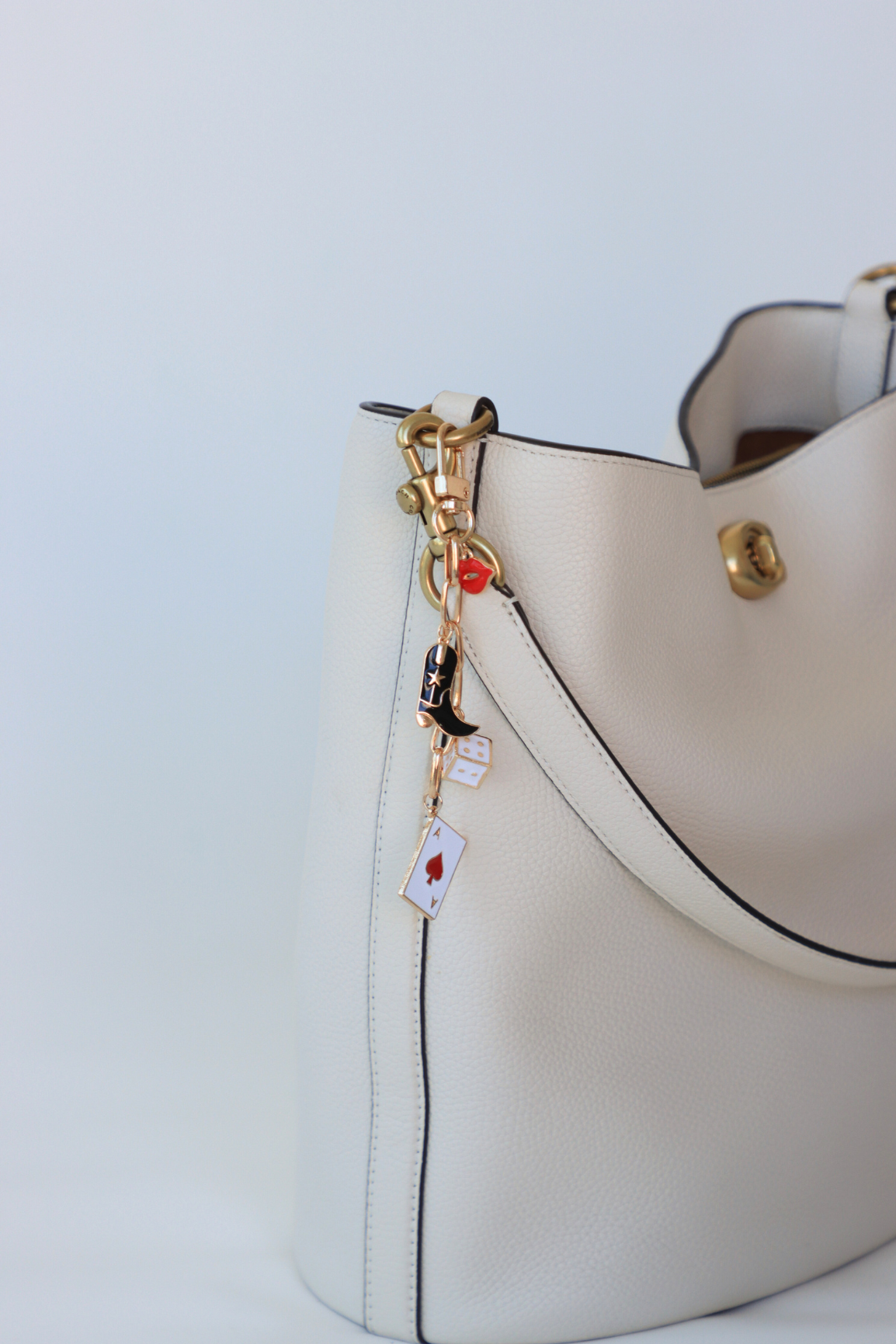 White handbag with decorative charm on a light blue background