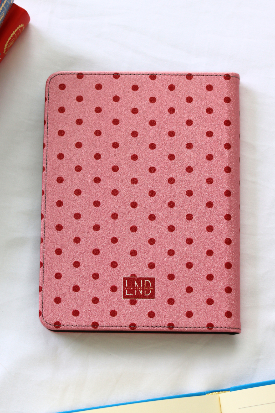 Pink polka dot kindle with a visible brand logo on a white surface