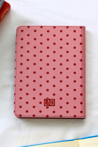 Pink polka dot kindle with a visible brand logo on a white surface