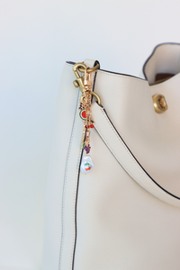 Close-up of a white handbag with a decorative charm on a light blue background