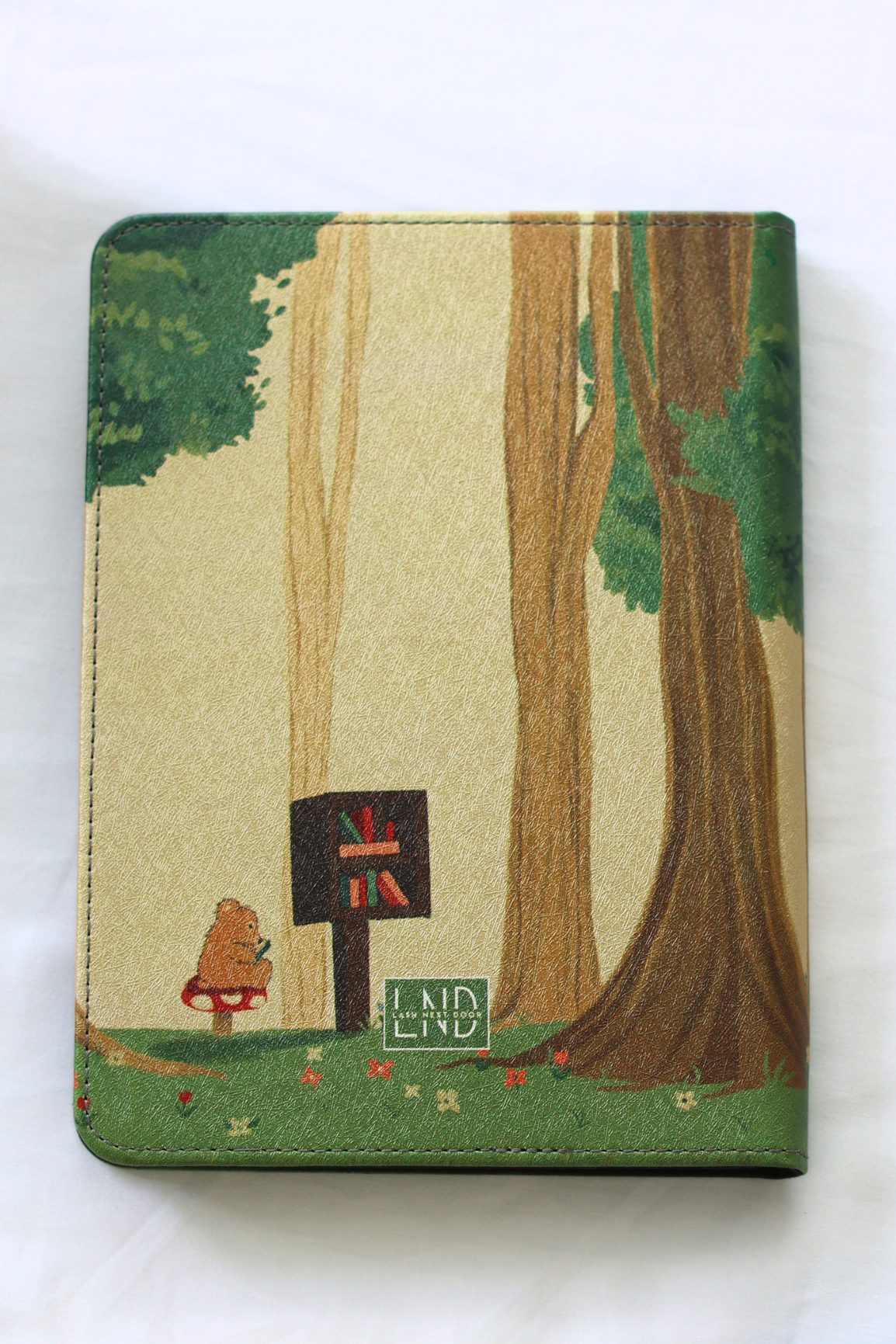 Kindle cover with forest design featuring trees, flowers, and a signpost on a white background