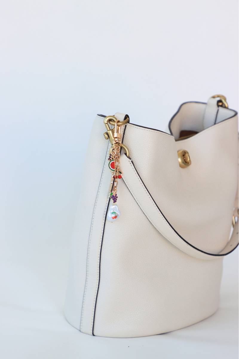 White handbag with decorative charm on a light blue background