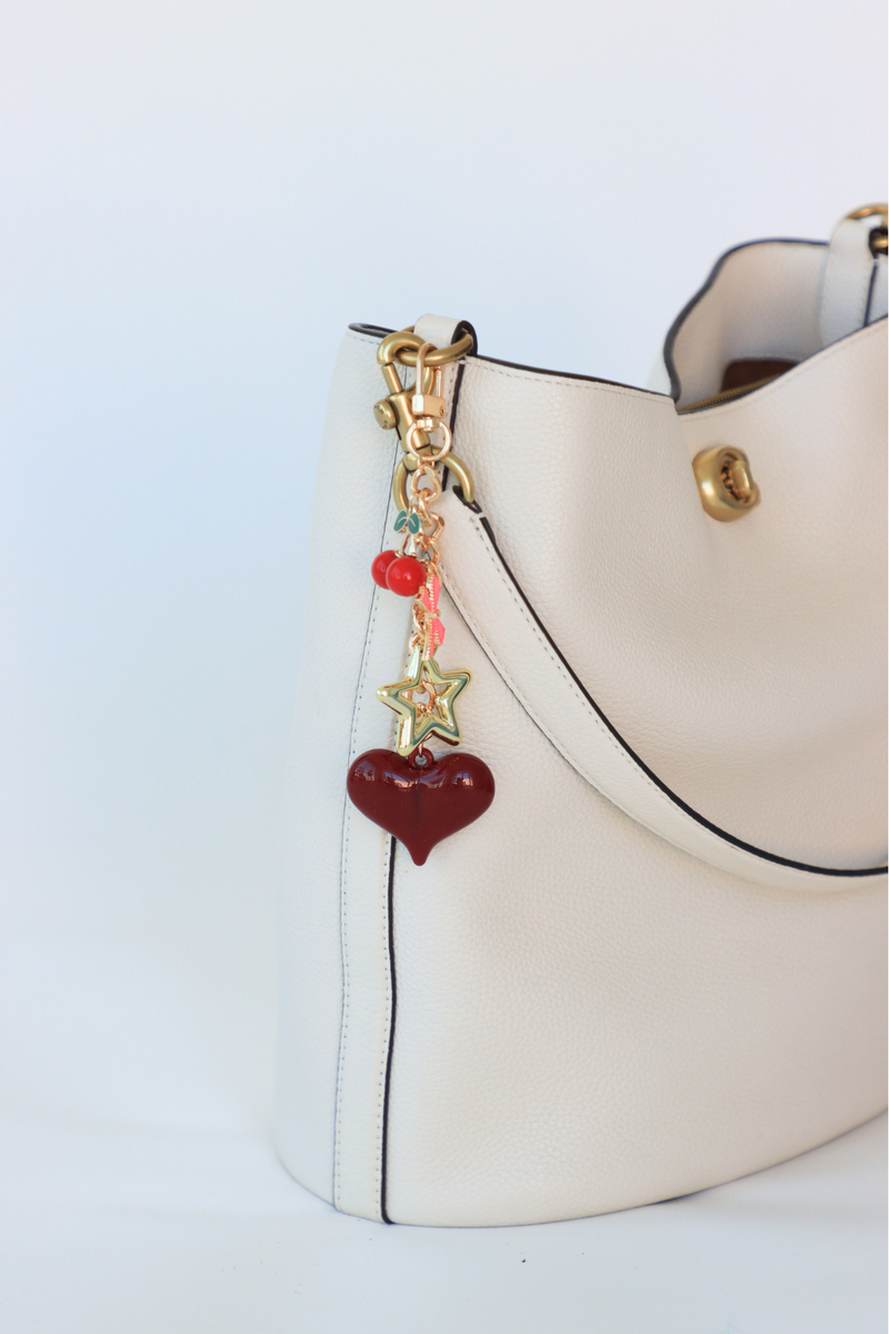 White handbag with a decorative charm on a light blue background