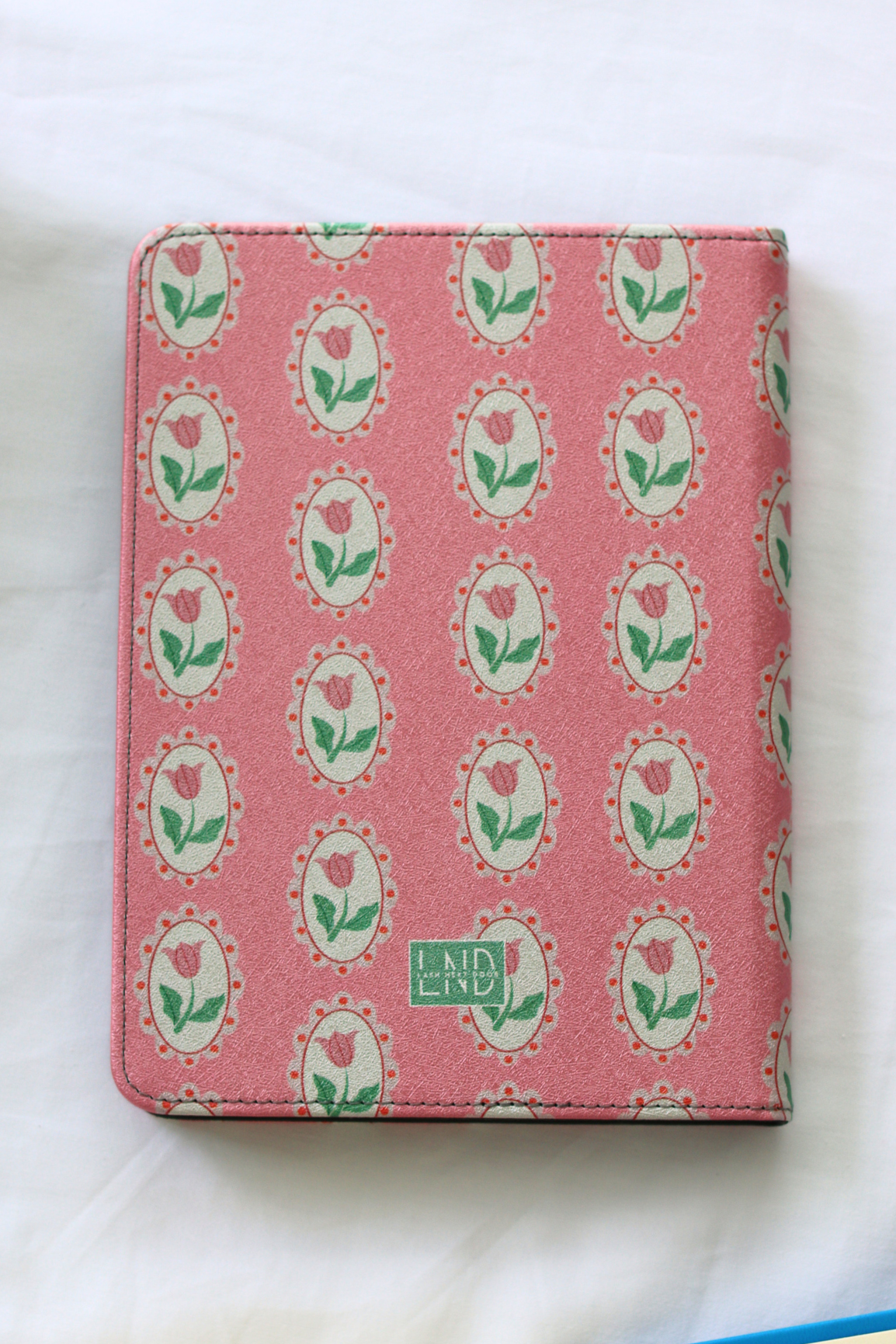 Pink kindle case with rose pattern and branding on a white background