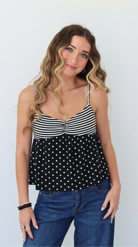 Woman wearing a black stripe and polka dot top against a white background 