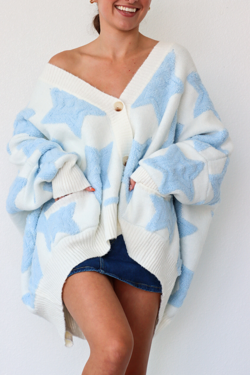 Person wearing a white and blue patterned cardigan over a denim skirt on a white background