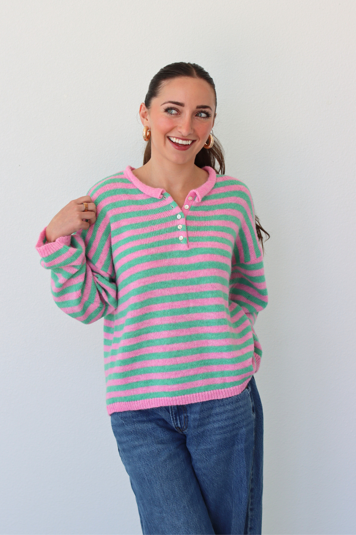 woman wearing a green and pink stripe sweater against a white background