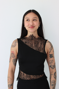 Woman wearing a black lace top against a white background