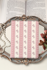 Pink patterned kindle on a decorative stand with a book and flowers in the background
