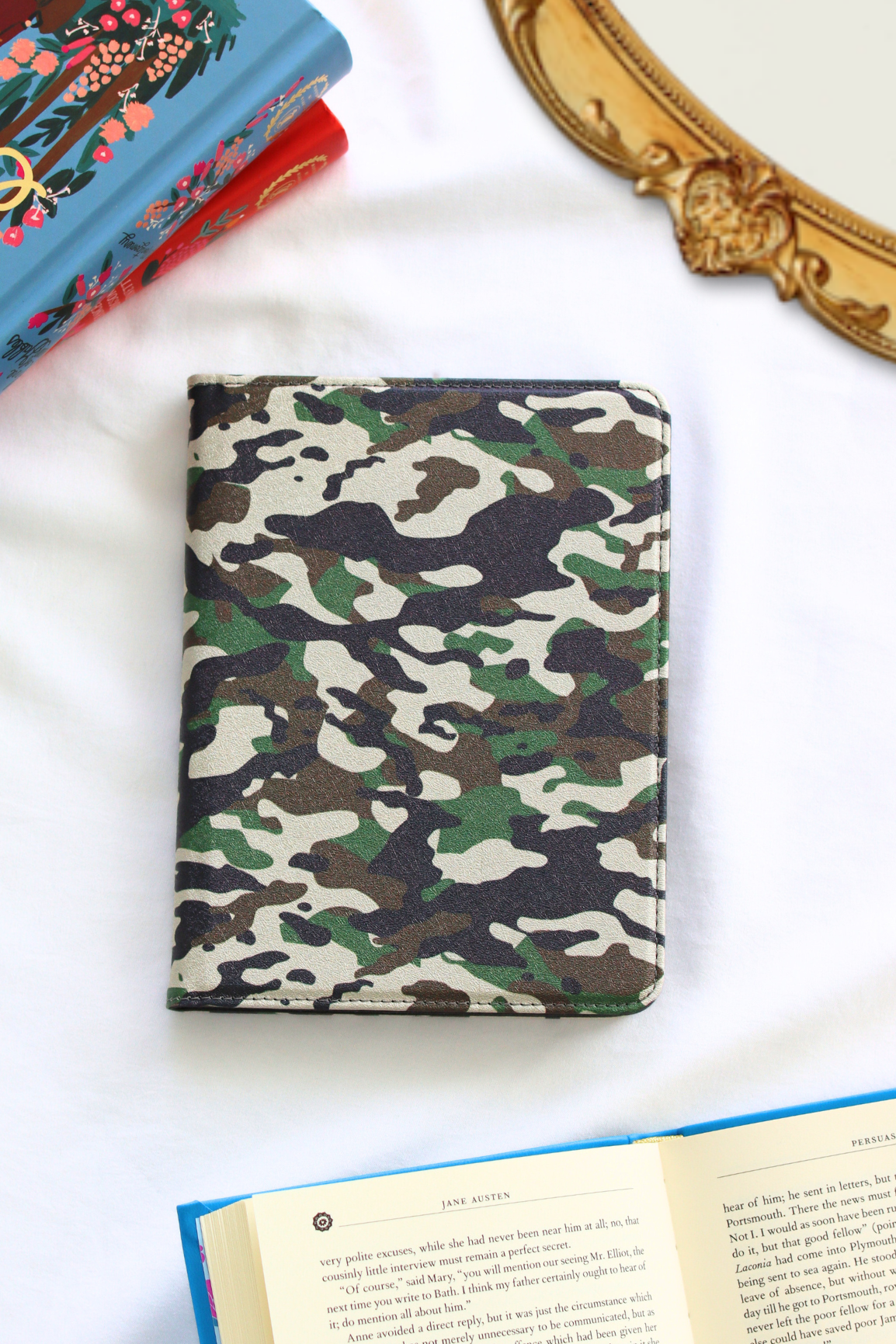 Camouflage-patterned kindle on a white surface with books in the background