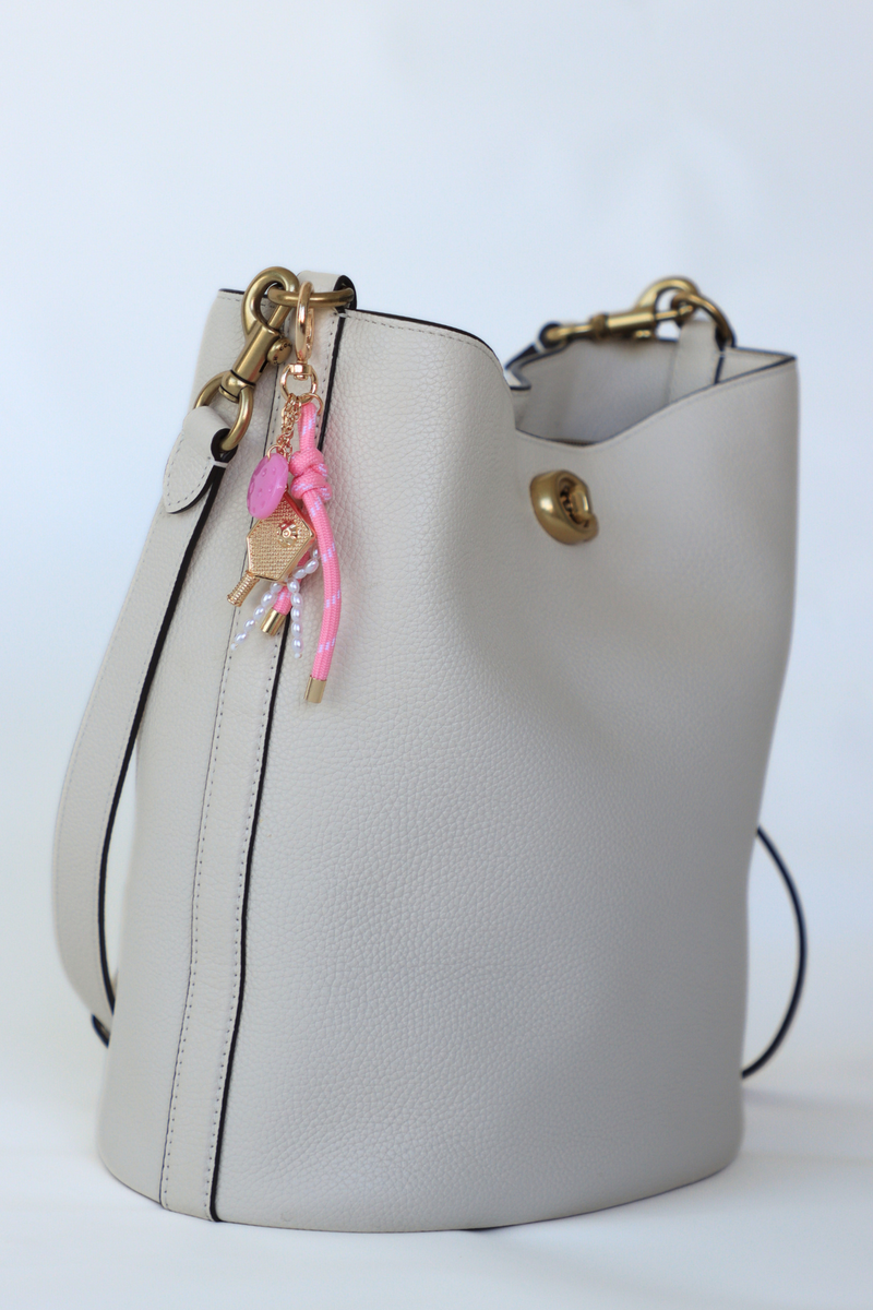 White bucket bag with gold and pink keychain on a white background