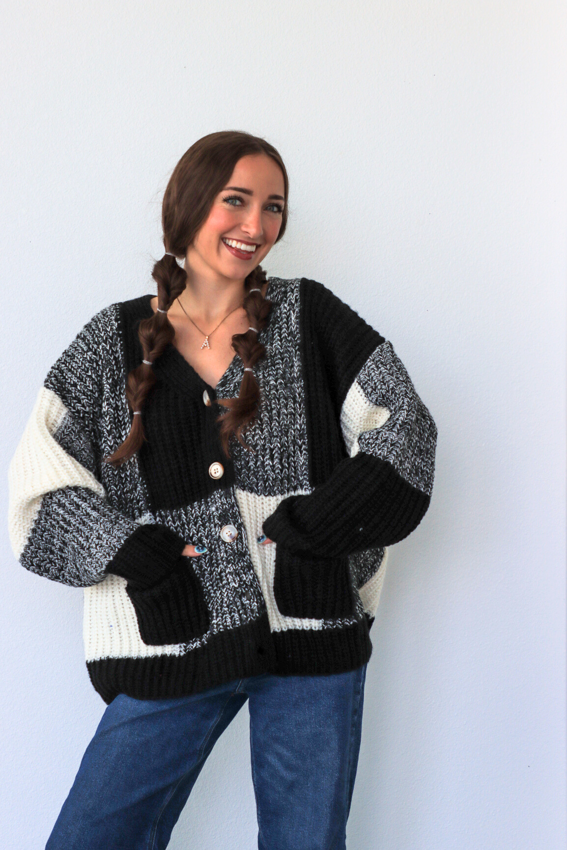 Woman wearing a black and white patterned cardigan against a light blue background