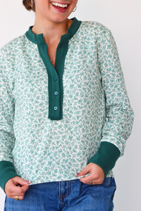 Person wearing a green and white patterned shirt with a plain background