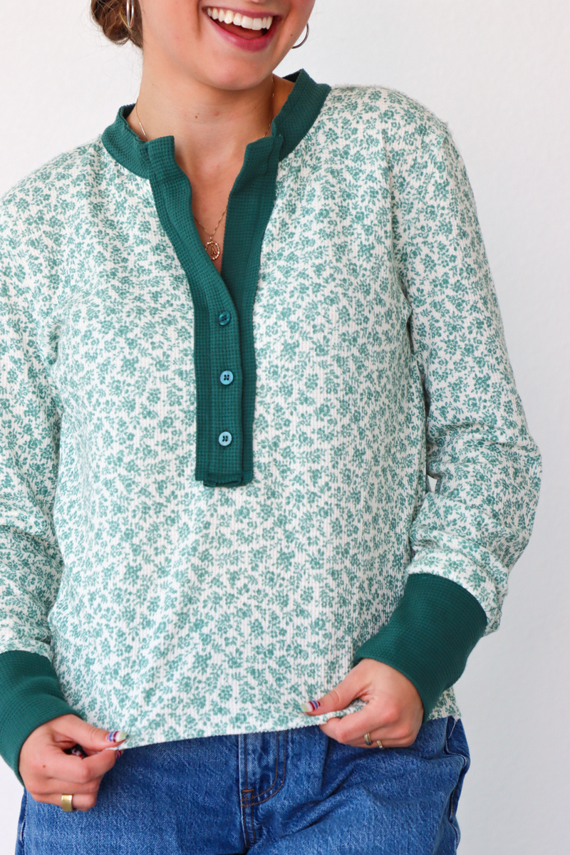 Person wearing a green and white patterned shirt with a plain background