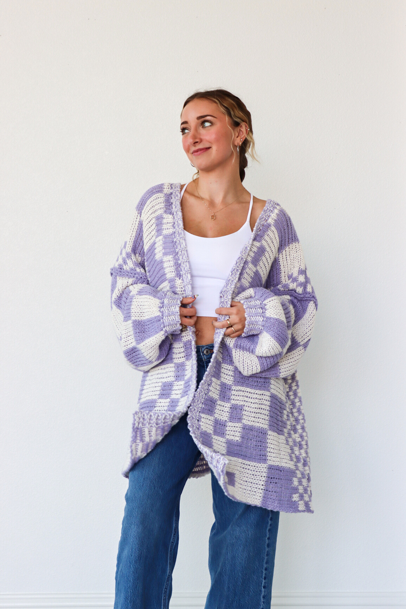 Woman wearing a purple and white checkered cardigan against a white background