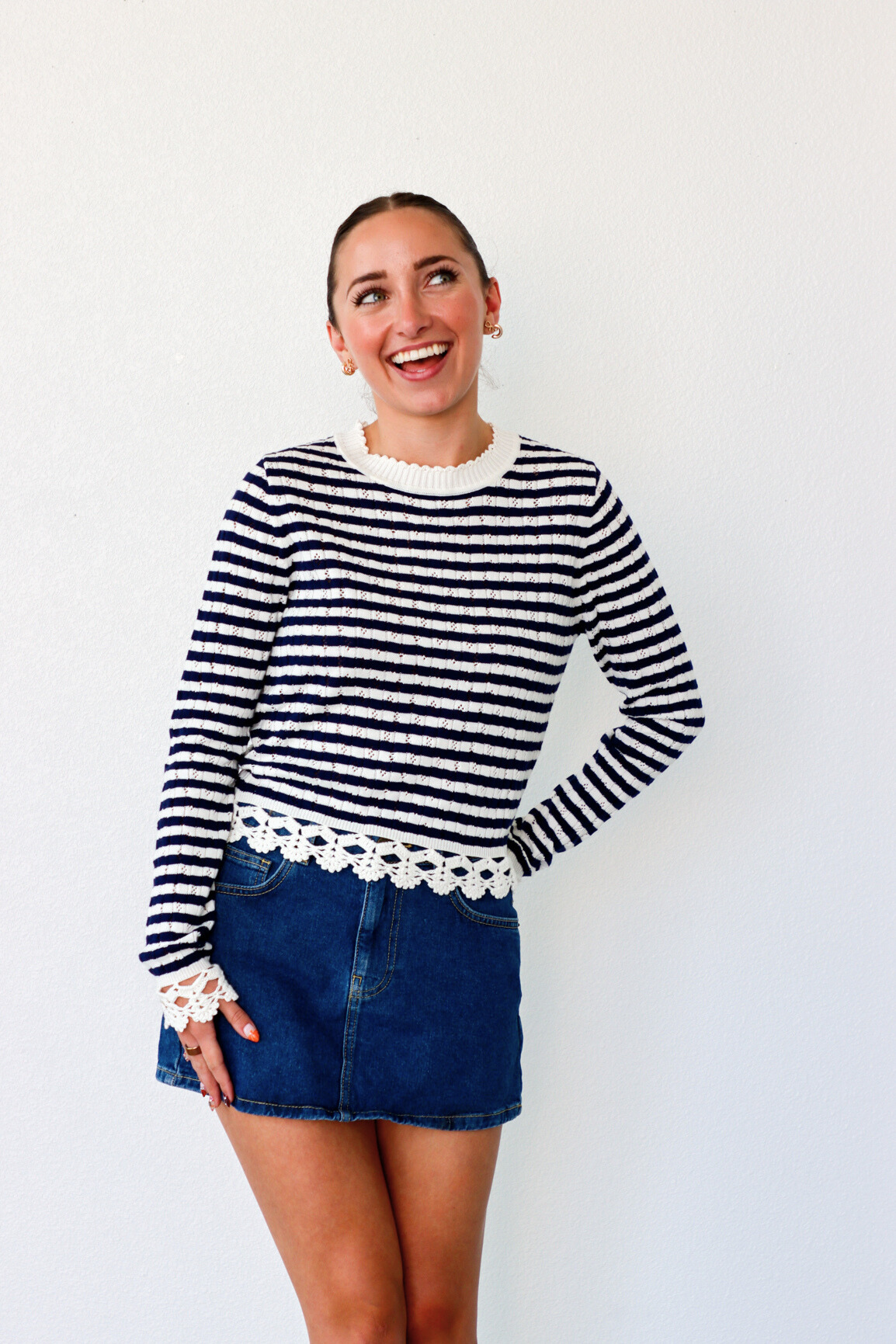 Woman wearing a black and white striped sweater with lace trim against a white background