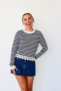 Woman wearing a black and white striped sweater with lace trim against a white background