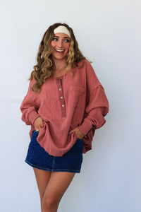 Woman wearing a pink long-sleeve shirt and blue denim skirt against a white background