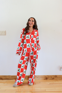 Woman wearing a red and white checkered pajama set with holly design in a room.