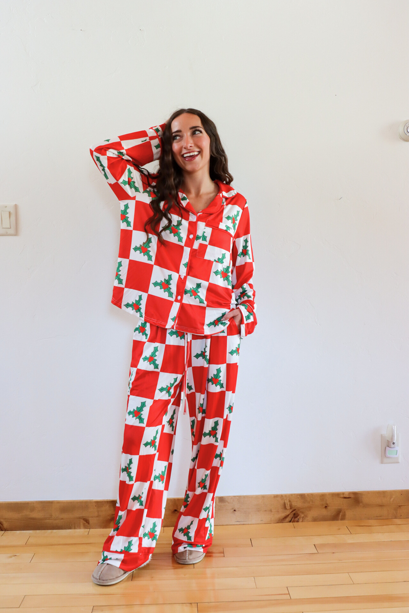 Woman wearing a red and white checkered pajama set with holly design indoors.