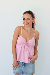 Woman wearing a pink tank top and denim skirt against a white background
