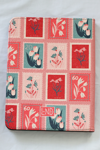 A nook case featuring a vintage-style postage stamp pattern with red, pink, and teal floral designs, photographed on a light fabric background.