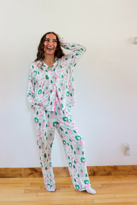 Woman wearing a patterned pajama set in a room with a white wall and wooden floor.