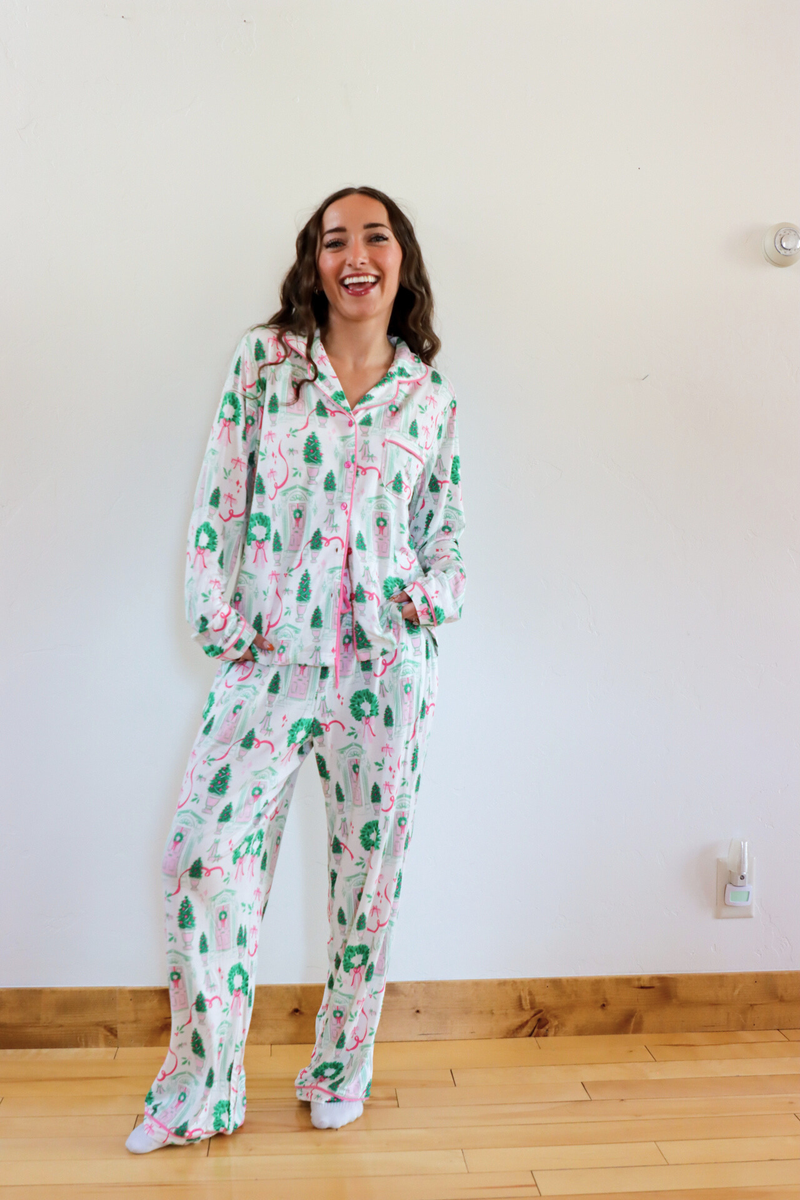 Woman wearing a floral onesie standing against a white wall.