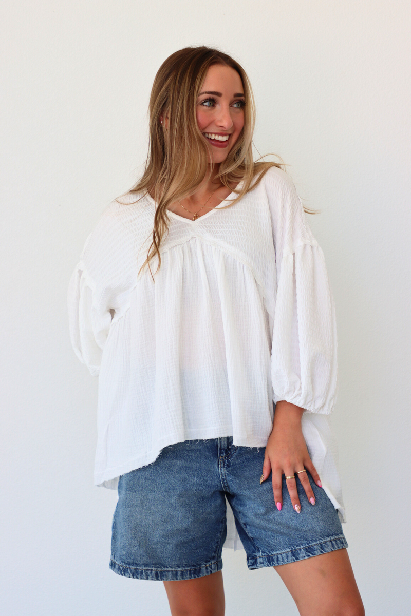 Woman wearing a white blouse and denim shorts against a white background