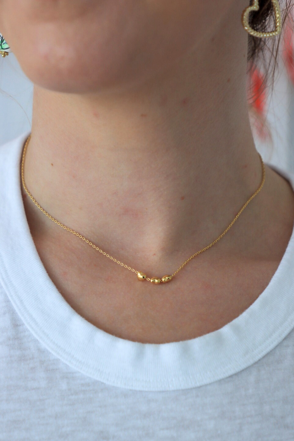 Gold necklace worn by a person with a white shirt background