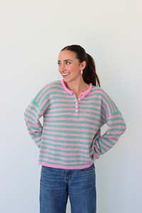 woman wearing a green and pink stripe sweater against a white background