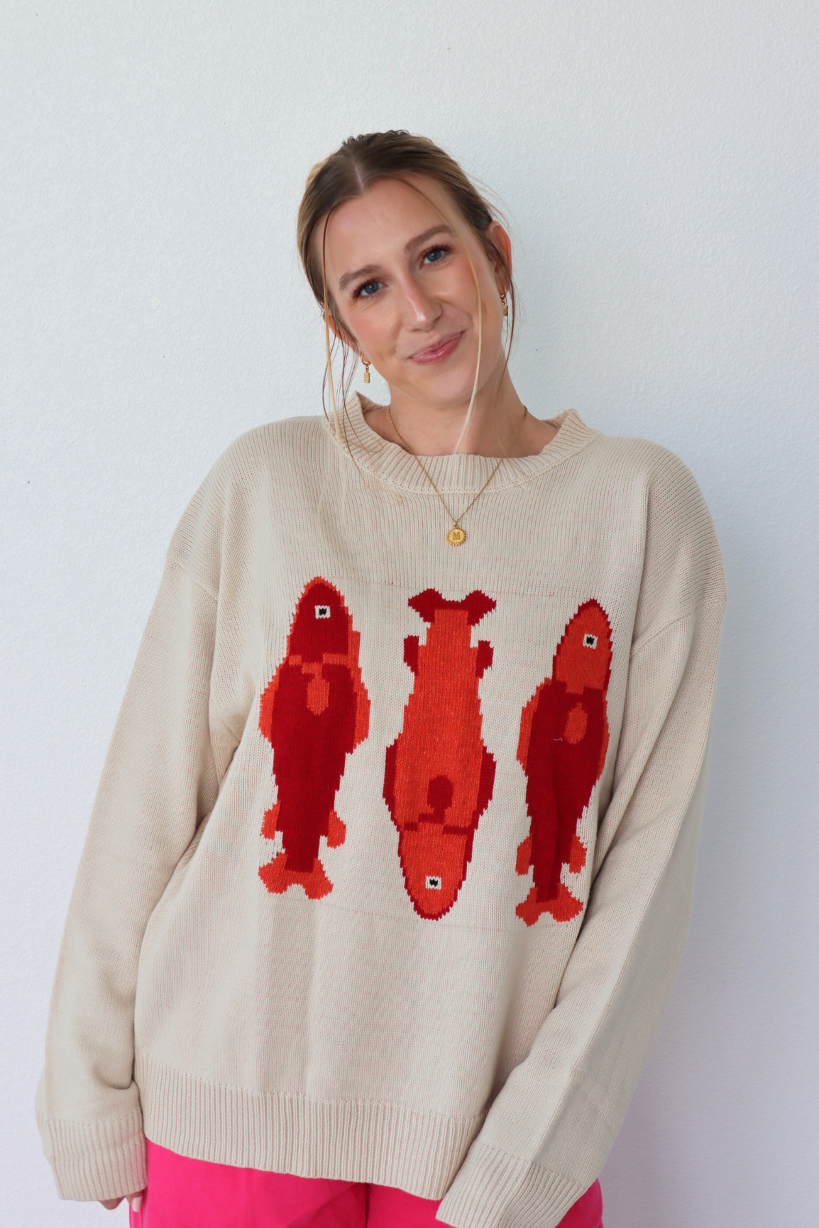 Woman wearing a beige sweater with red dog illustrations against a white background