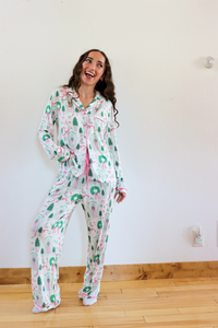 Woman wearing a floral pajama set in a room with a white wall and wooden floor.