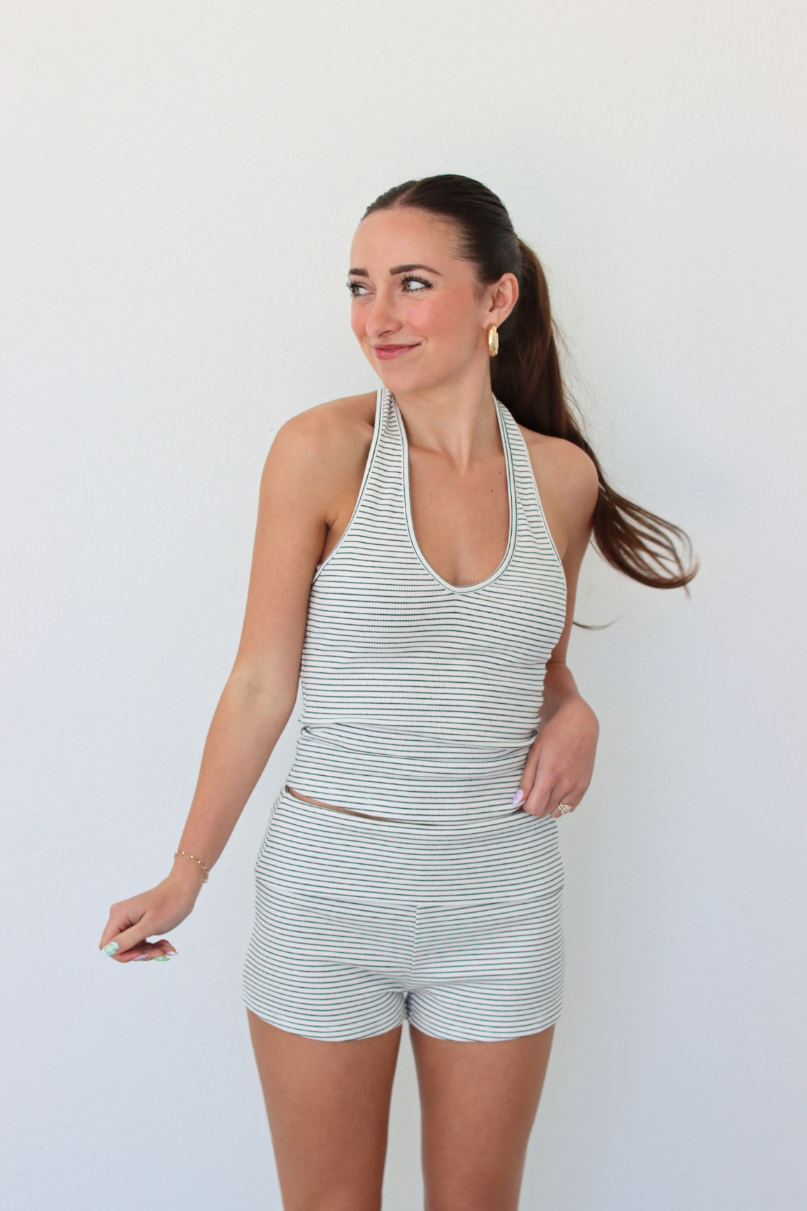 Woman wearing a striped halter tank top and shorts set against a white background