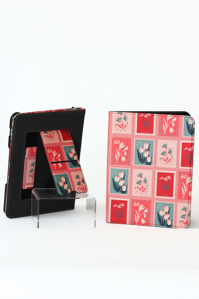 A nook case with a vintage postage stamp pattern in red, pink, and teal, shown both closed and open on a clear acrylic stand against a white background.