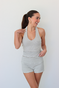 Woman wearing a striped halter tank top and shorts set against a white background