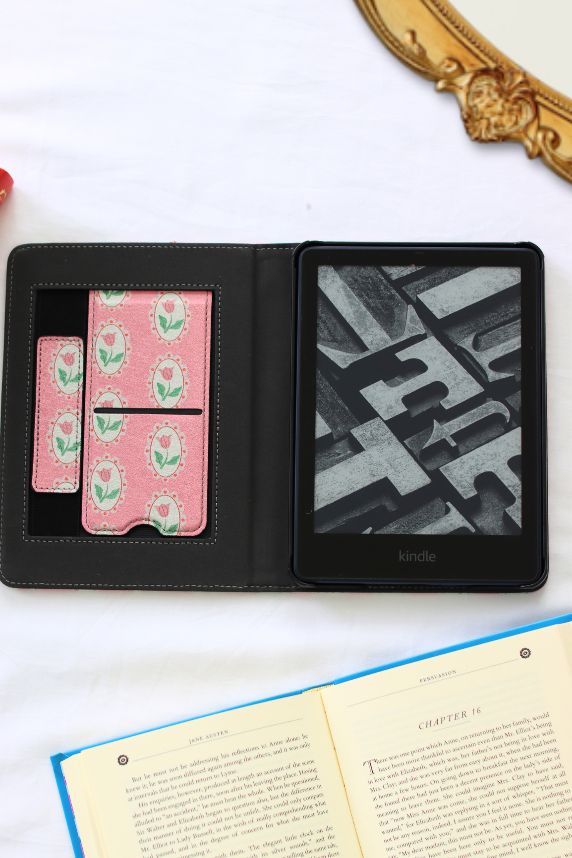 Black Kindle e-reader with pink floral case on a white surface
