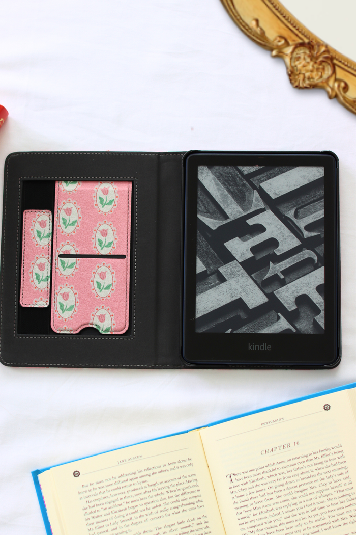 Black Kindle e-reader with pink floral case on a white surface