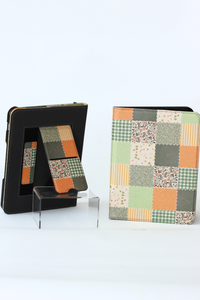 A nook case set displayed on a white background, including a black protective outer case, a fold-out kickstand, and a matching patchwork-patterned folio cover with orange, green, beige, and gray squares.