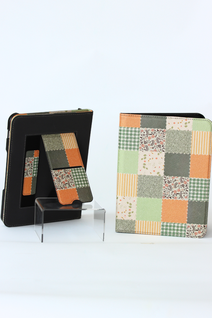 A nook case set displayed on a white background, including a black protective outer case, a fold-out kickstand, and a matching patchwork-patterned folio cover with orange, green, beige, and gray squares.