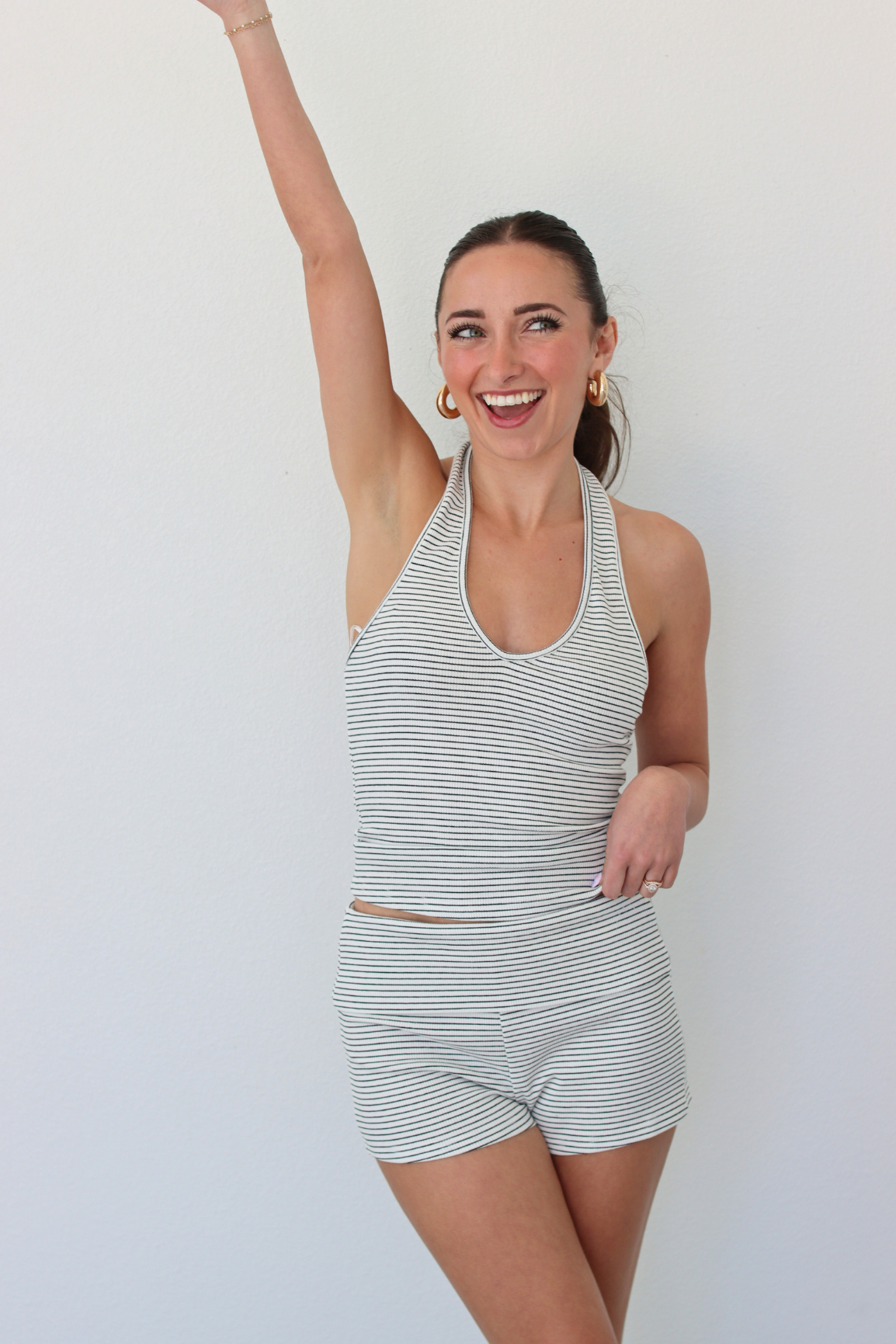 Woman wearing a striped halter tank top and shorts set against a white background