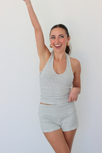 Woman wearing a striped halter tank top and shorts set against a white background