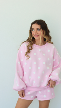 Woman wearing a pink polka dot outfit against a white background