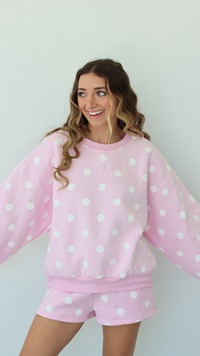 Woman wearing a pink polka dot outfit against a white background