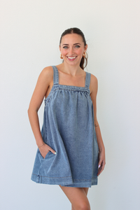 Woman wearing a denim blue mini dress against a white background