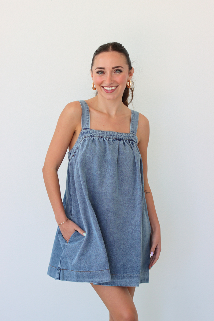 Woman wearing a denim blue mini dress against a white background