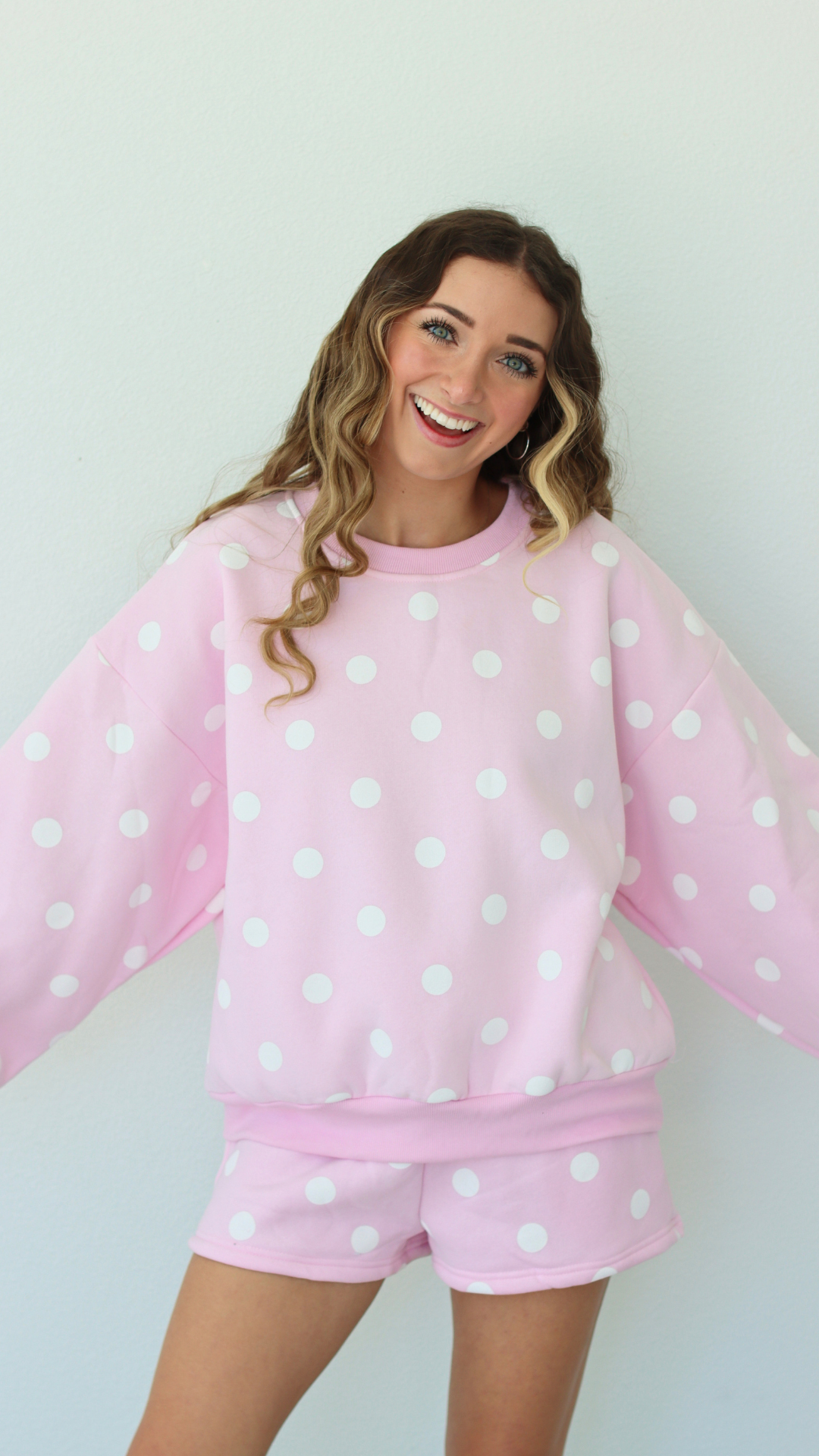 Woman wearing a pink polka dot outfit against a white background