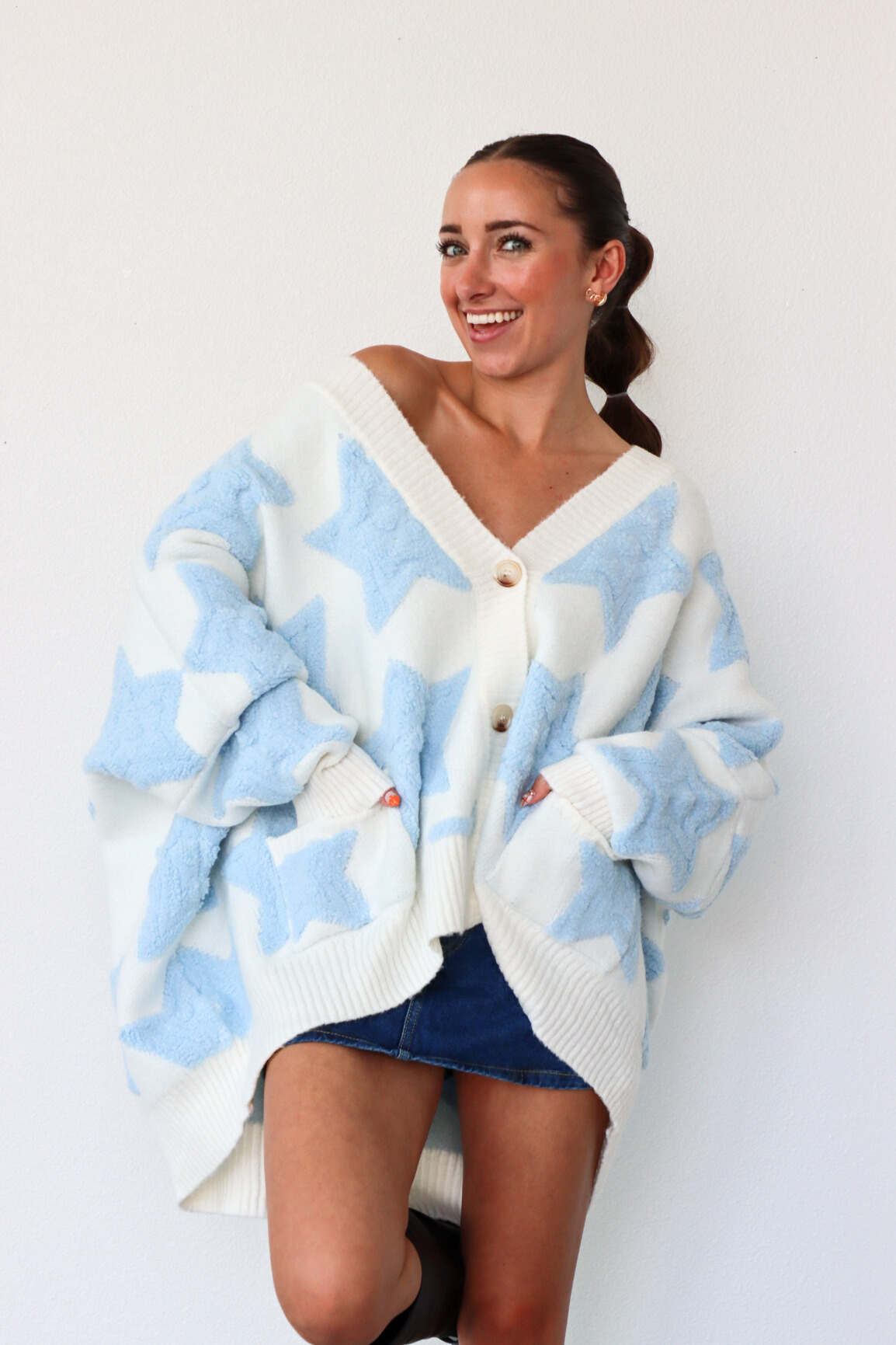 Woman wearing a blue and white patterned cardigan against a white background