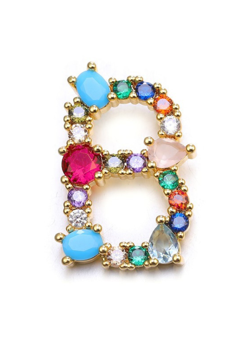 Colorful gemstone brooch with gold frame on a white background